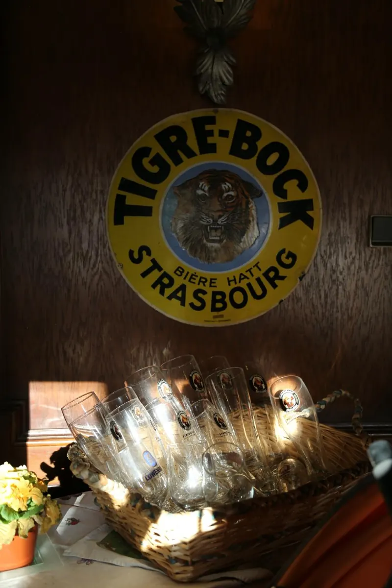 Une vieille plaque émaillée de bière alsacienne et des verres dans la salle