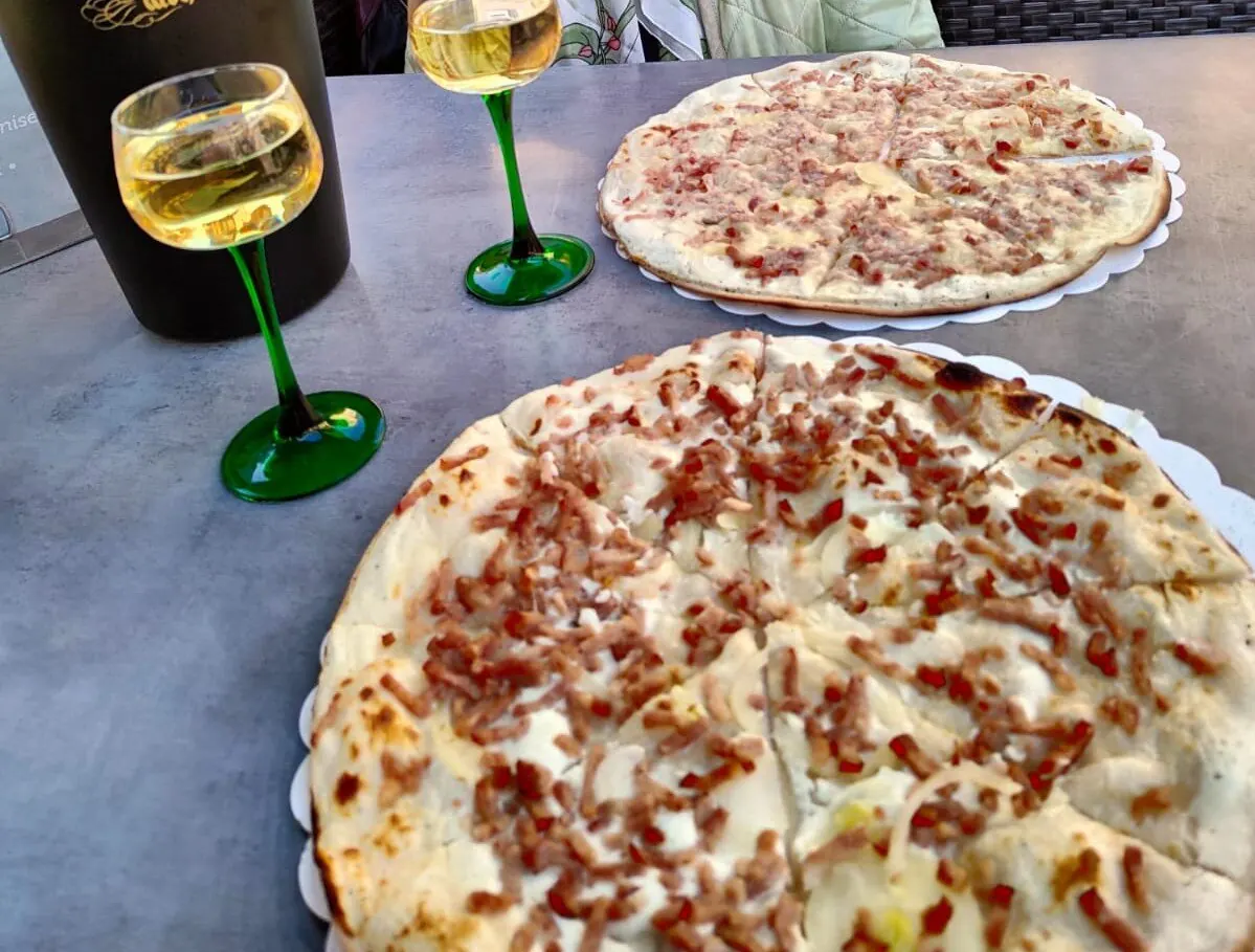 Deux tartes flambées et des verres à vin d'Alsace à pied vert
